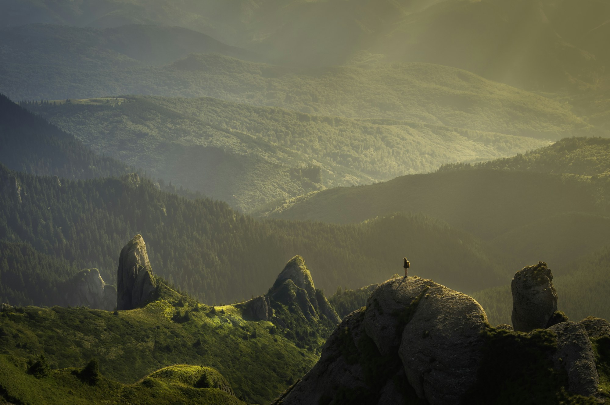 A traveller looking out across green mountain cliffs
